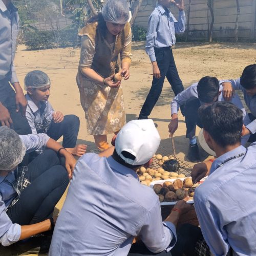 VidyaGyan School Environment Club students roasting potatoes around an open fire for their 60 for Sustainability