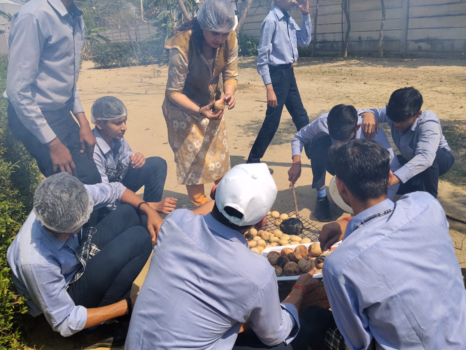 VidyaGyan School Environment Club students roasting potatoes around an open fire for their 60 for Sustainability